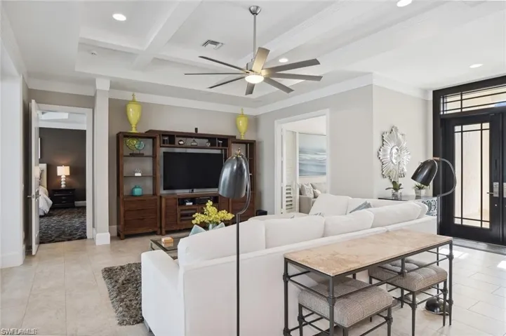 Living area with coffered ceiling, a ceiling fan, beamed ceiling, crown molding, and recessed lighting