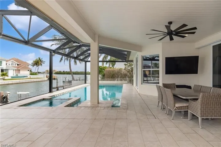 View of pool featuring a water view, a patio area, a lanai, and a ceiling fan