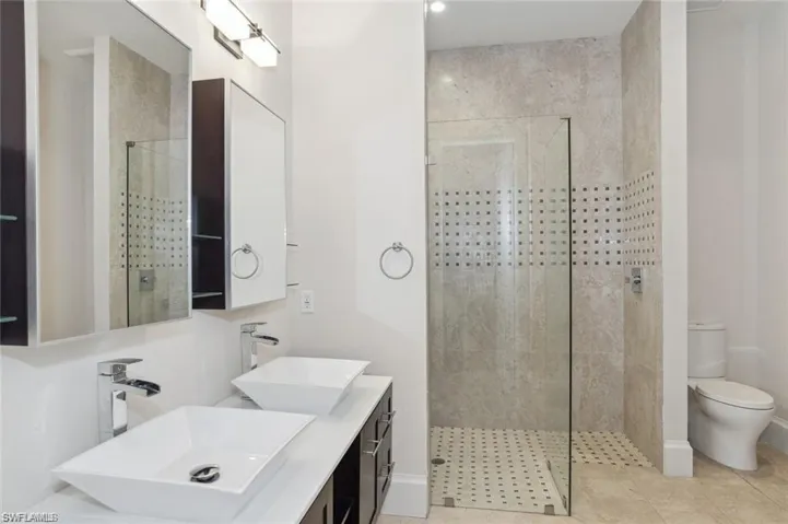 #2 Full bathroom main level with toilet, a shower stall, double vanity, and a sink