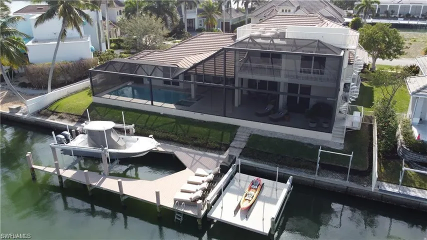 View of dock featuring an outdoor pool, a patio, boat lift, a water view, and a lanai