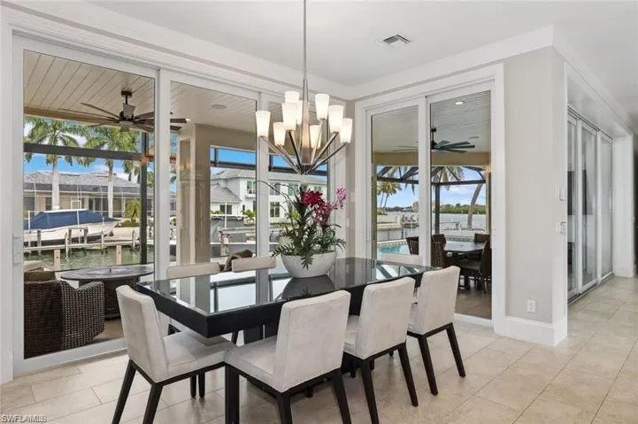 Dining area with ceiling fan with notable chandelier, visible vents, baseboards, and light tile patterned flooring