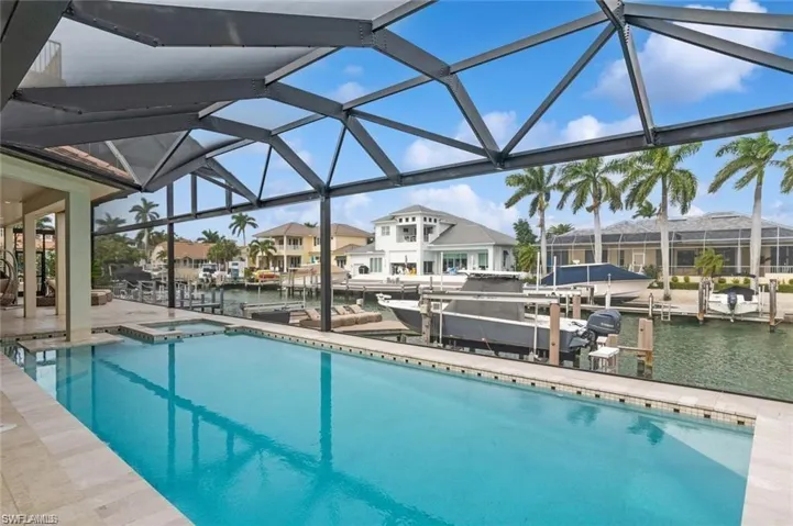 Pool with a boat dock, glass enclosure, boat lift, a residential view, and a water view