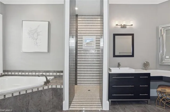 Full bathroom with tiled shower, vanity, and a bath