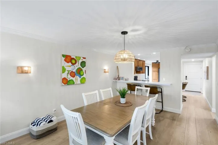 Dining space with ornamental molding, light wood finished floors, and recessed lighting