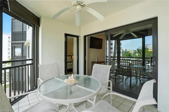 Tiled balcony with a ceiling fan, black metal railings, and a glass sliding door