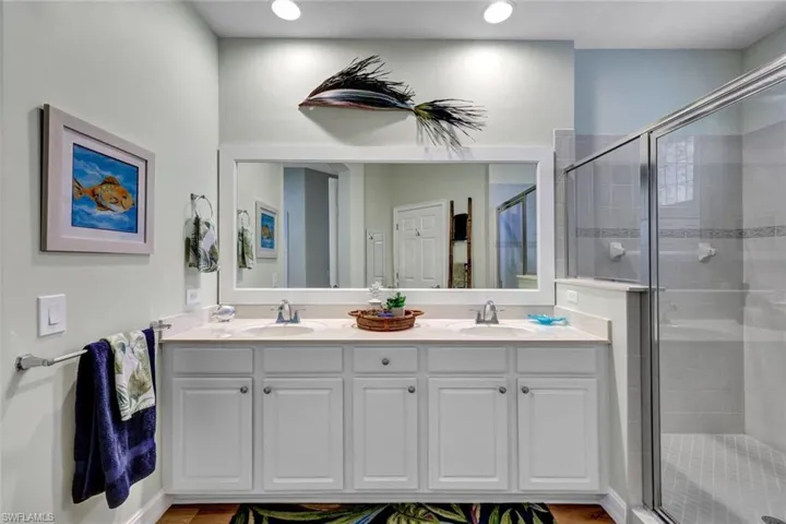 Bathroom featuring dual vanity and a shower with door