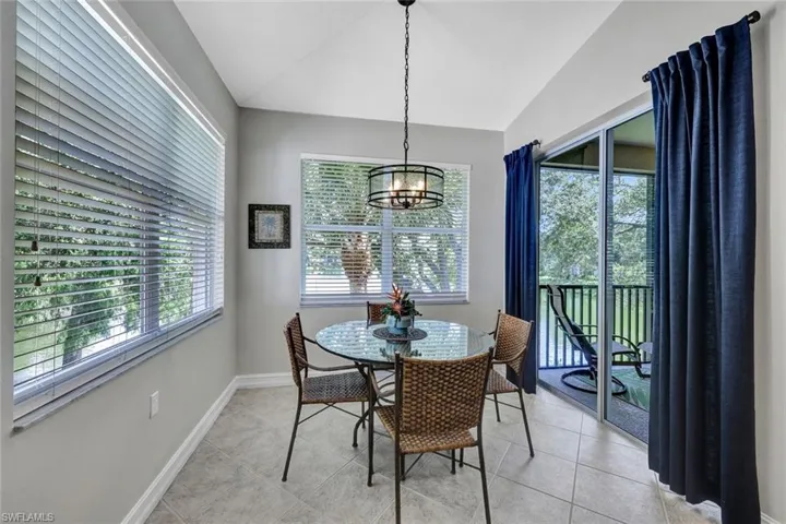 Dining room featuring a notable chandelier, light tile flooring, and lofted ceiling