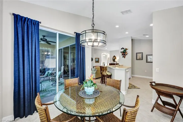 Dining room with light tile floors and ceiling fan with notable chandelier