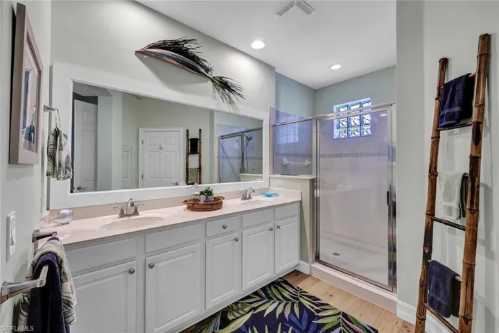 Bathroom with dual vanity, an enclosed shower, and hardwood / wood-style flooring