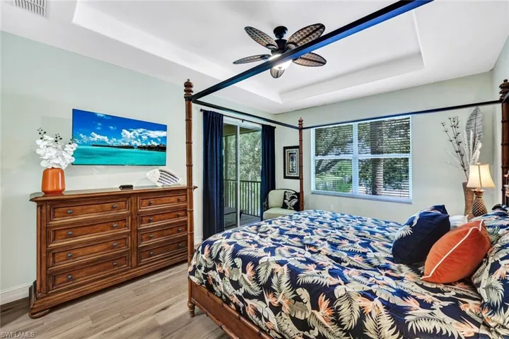 Bedroom featuring ceiling fan, a raised ceiling, light hardwood / wood-style floors, and access to outside