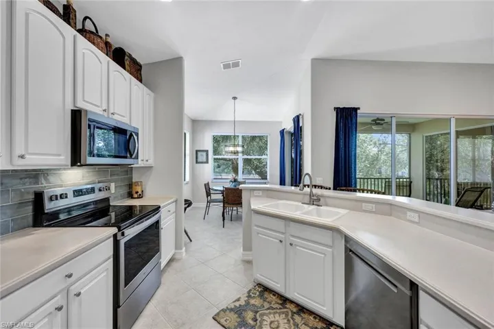 Kitchen featuring pendant lighting, light tile floors, sink, white cabinetry, and appliances with stainless steel finishes
