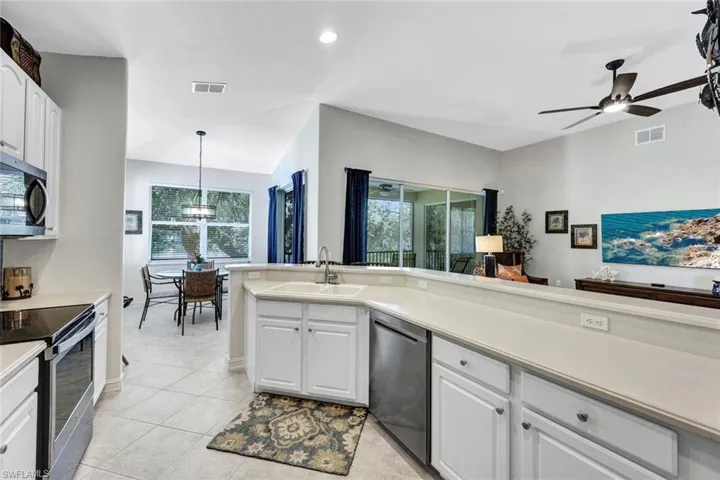 Kitchen with appliances with stainless steel finishes, a healthy amount of sunlight, sink, and light tile flooring