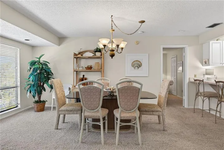 Dining area with light colored carpet, a textured ceiling, and a chandelier