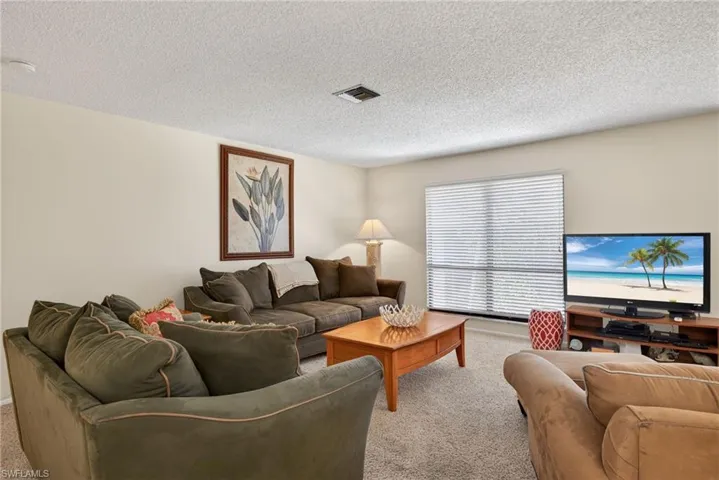 Living area featuring light colored carpet and a textured ceiling