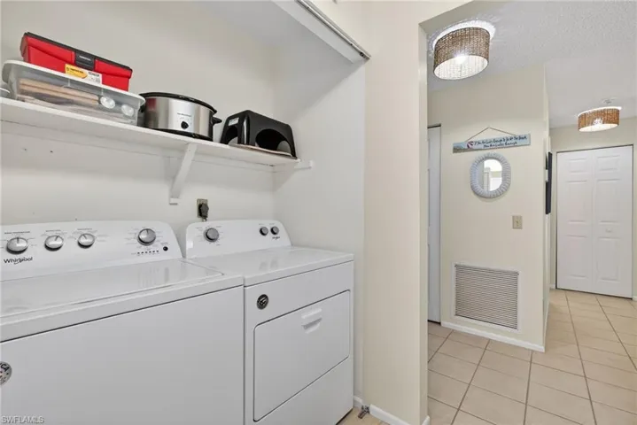 Laundry area featuring washer and clothes dryer, light tile patterned floors, and a textured ceiling