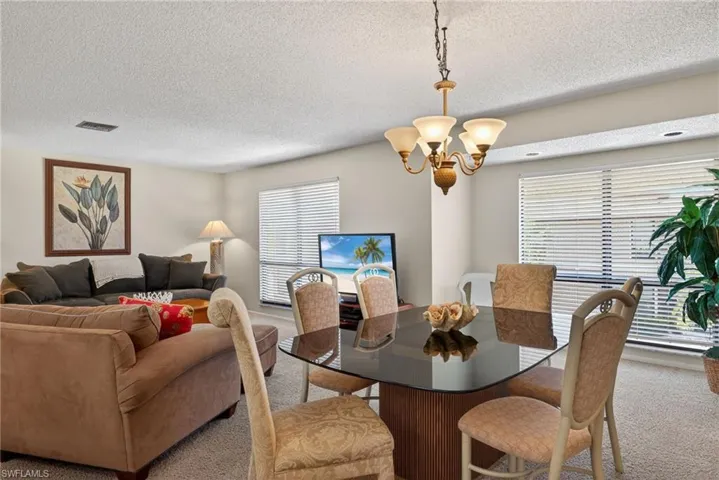Carpeted dining area featuring a textured ceiling and a chandelier