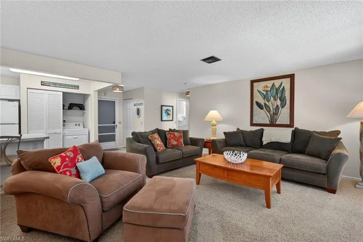 Living area with carpet floors, a textured ceiling, and washer / clothes dryer