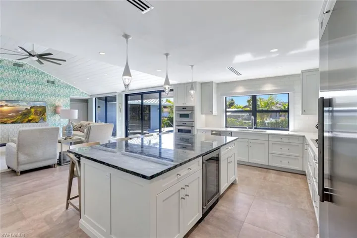 Kitchen with a center island, hanging light fixtures, white cabinetry, stainless steel appliances, and beverage cooler