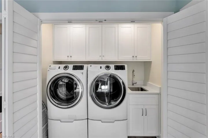Washroom with cabinets, independent washer and dryer, and sink