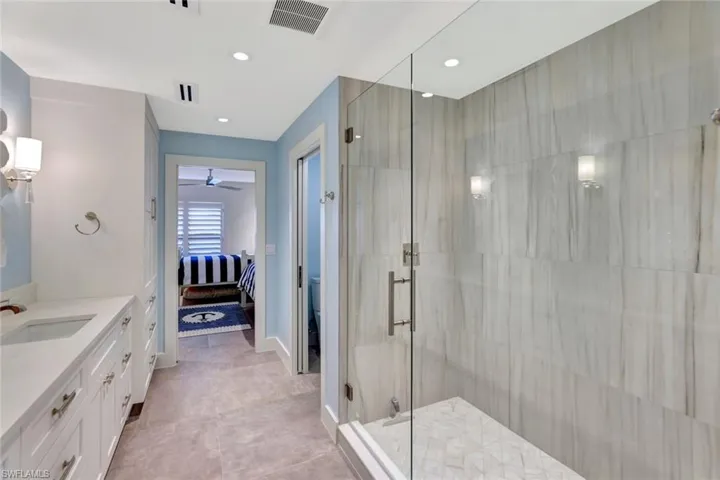 Bathroom featuring ceiling fan, tile patterned floors, an enclosed shower, toilet, and vanity