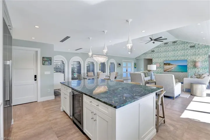 Kitchen featuring white cabinetry, beverage cooler, dark stone countertops, lofted ceiling, and a kitchen island