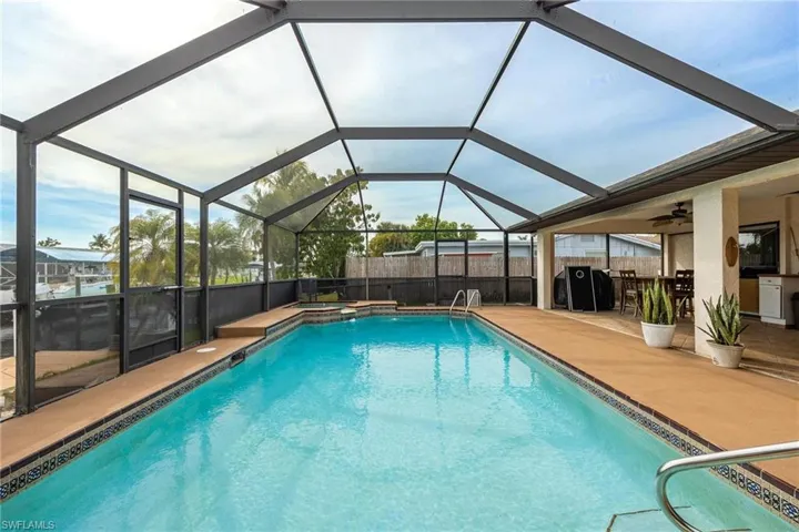 Relaxing pool / spa with glass enclosure, a sunroom, a patio, and area for grilling
