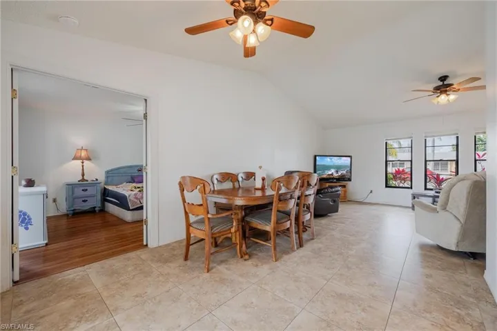 Dining area with a ceiling fan, vaulted ceiling, and light tile patterned floors