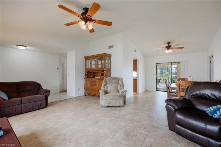 Living area featuring a ceiling fan, lofted ceiling, and light tile patterned floors