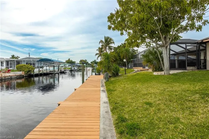 Dock with a sunroom, a lawn, a lanai, and a water view