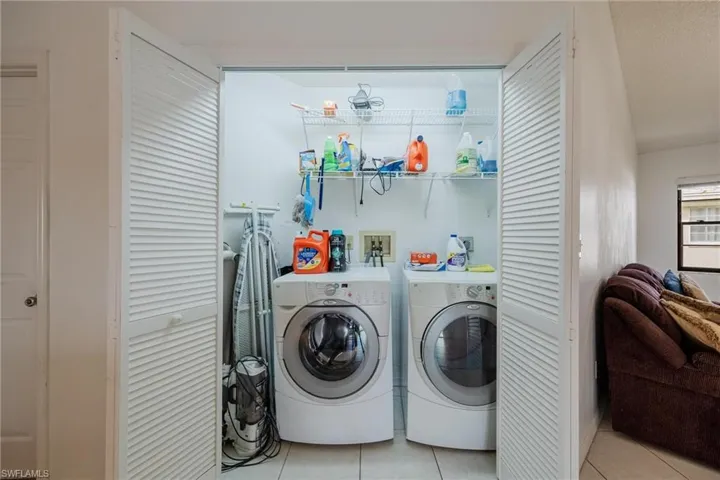Laundry area featuring light tile patterned floors and separate washer and dryer