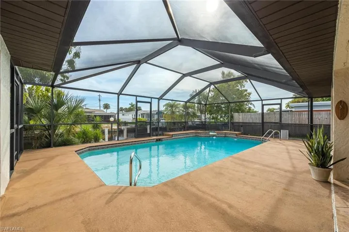 Outdoor pool with glass enclosure, a sunroom, and a patio area