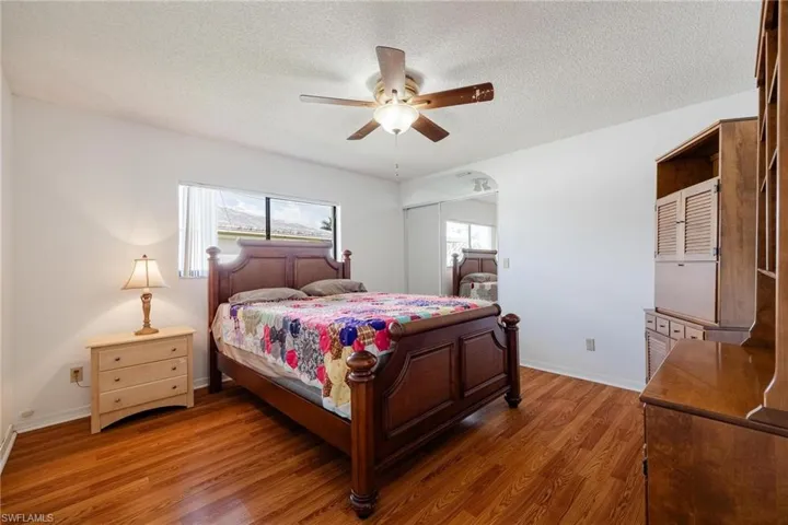 Bedroom featuring wood finished floors, ceiling fan, a textured ceiling, and a closet