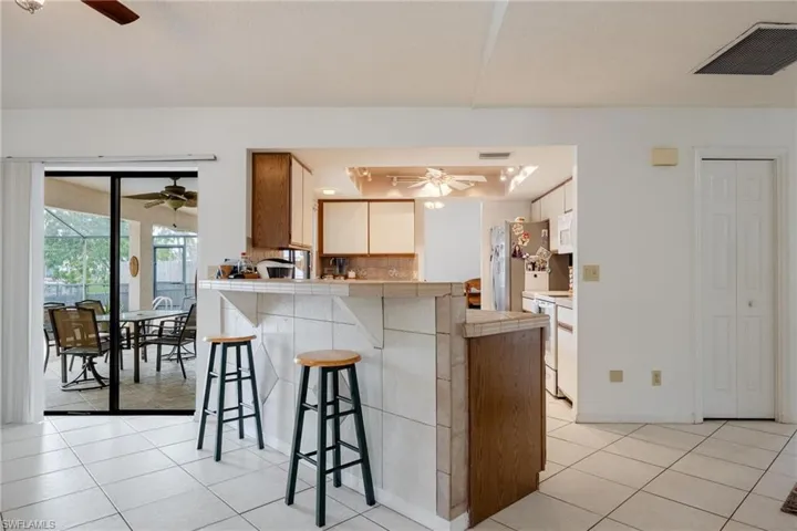 Kitchen featuring tile counters, a kitchen bar, ceiling fan, and wood finish cabinetry