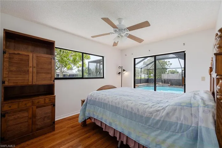 Bedroom featuring a sunroom, wood finished floors, a ceiling fan, access to outside, and a textured ceiling