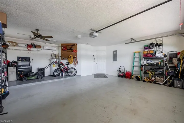 Garage featuring water heater, electric panel, ceiling fan, and a garage door opener