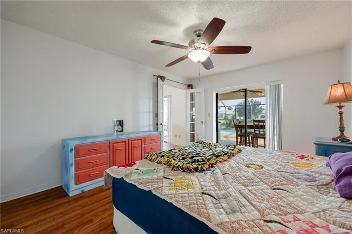 Bedroom with access to exterior, a textured ceiling, dark wood-style floors, a ceiling fan, and french doors