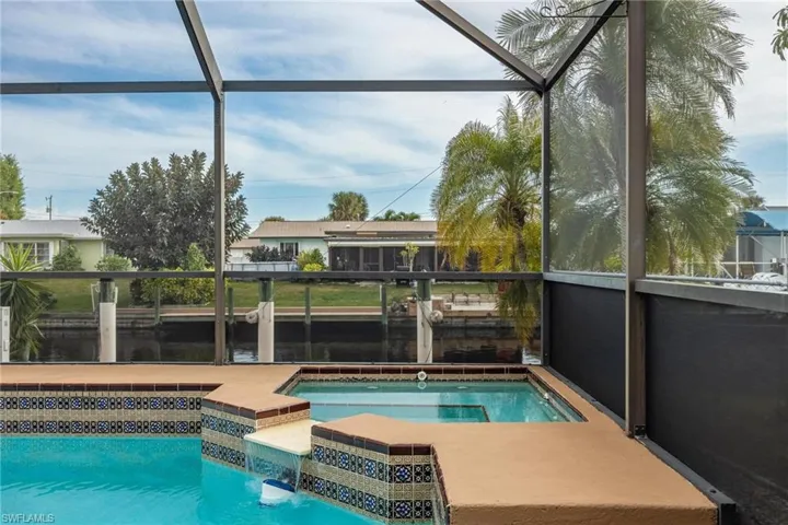 Outdoor pool featuring glass enclosure, an in-ground hot tub, and a sunroom