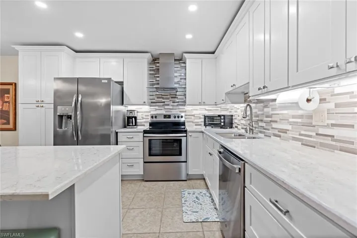 Kitchen with stainless steel appliances, sink, and white cabinets