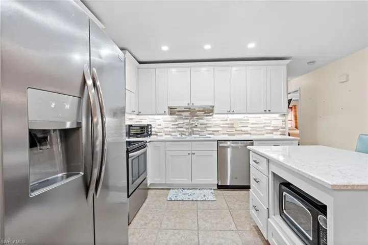 Kitchen featuring appliances with stainless steel finishes, sink, white cabinets, and backsplash
