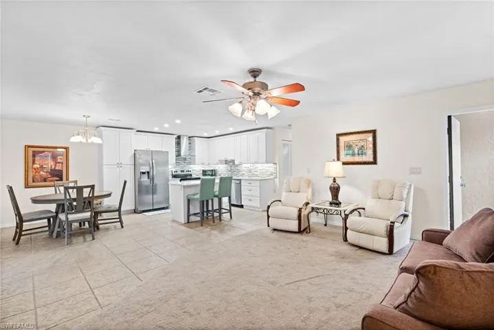 Carpeted living room featuring ceiling fan with notable chandelier