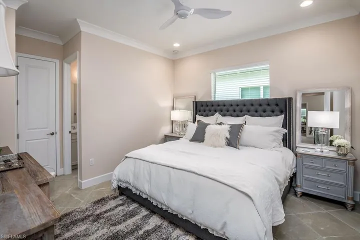 Tiled bedroom with ceiling fan and crown molding