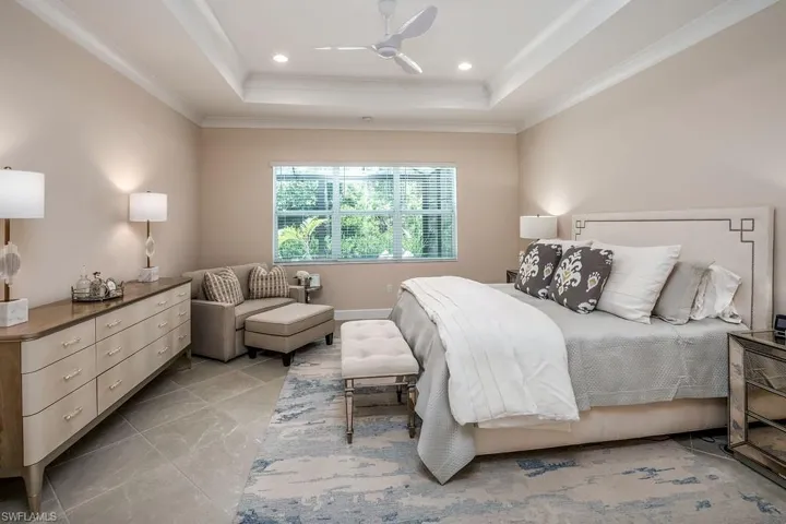 Bedroom featuring ceiling fan, light tile floors, and a raised ceiling