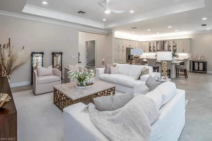 Living room featuring ceiling fan, a tray ceiling, light tile floors, and crown molding