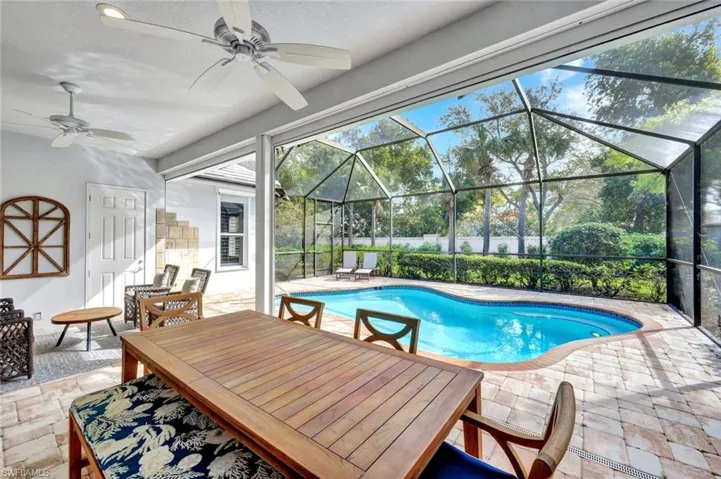 View of swimming pool featuring outdoor dining space, patio surround, a sunroom, and glass enclosure