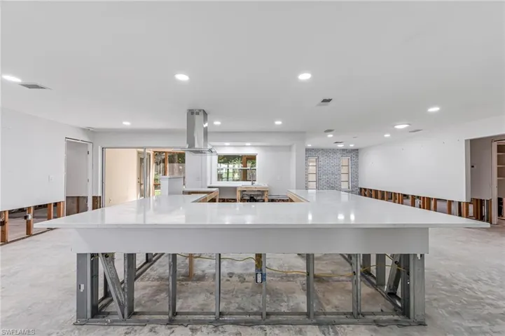 Kitchen with a large island, island range hood, and concrete floors