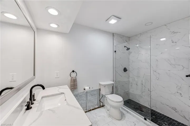 Bathroom featuring a tile shower, vanity, and toilet