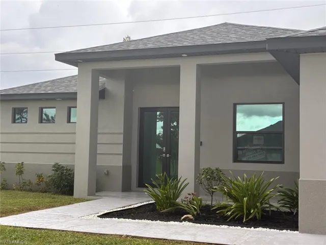 Doorway to property featuring a shingled roof, stucco siding, and french doors
