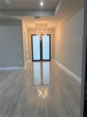 Empty room with a chandelier, a raised ceiling, and recessed lighting