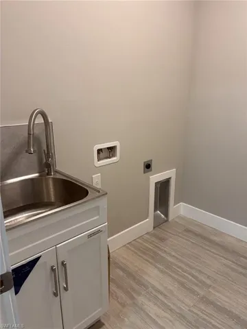 Laundry room featuring light wood-style floors, hookup for a washing machine, cabinet space, and hookup for an electric dryer