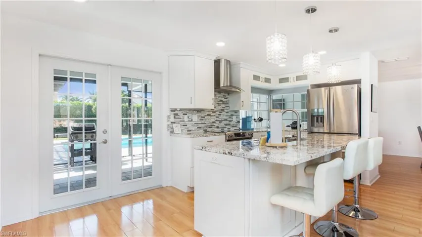 Kitchen with french doors, white cabinetry, light stone counters, and stainless steel appliances